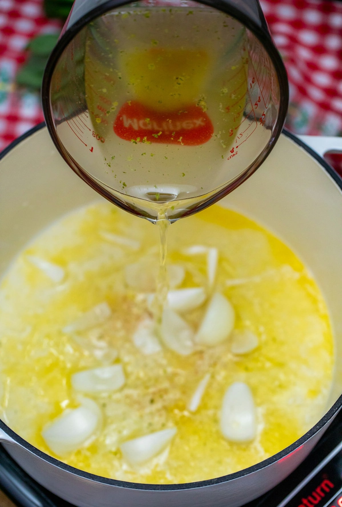 Pouring chicken stock into dutch oven