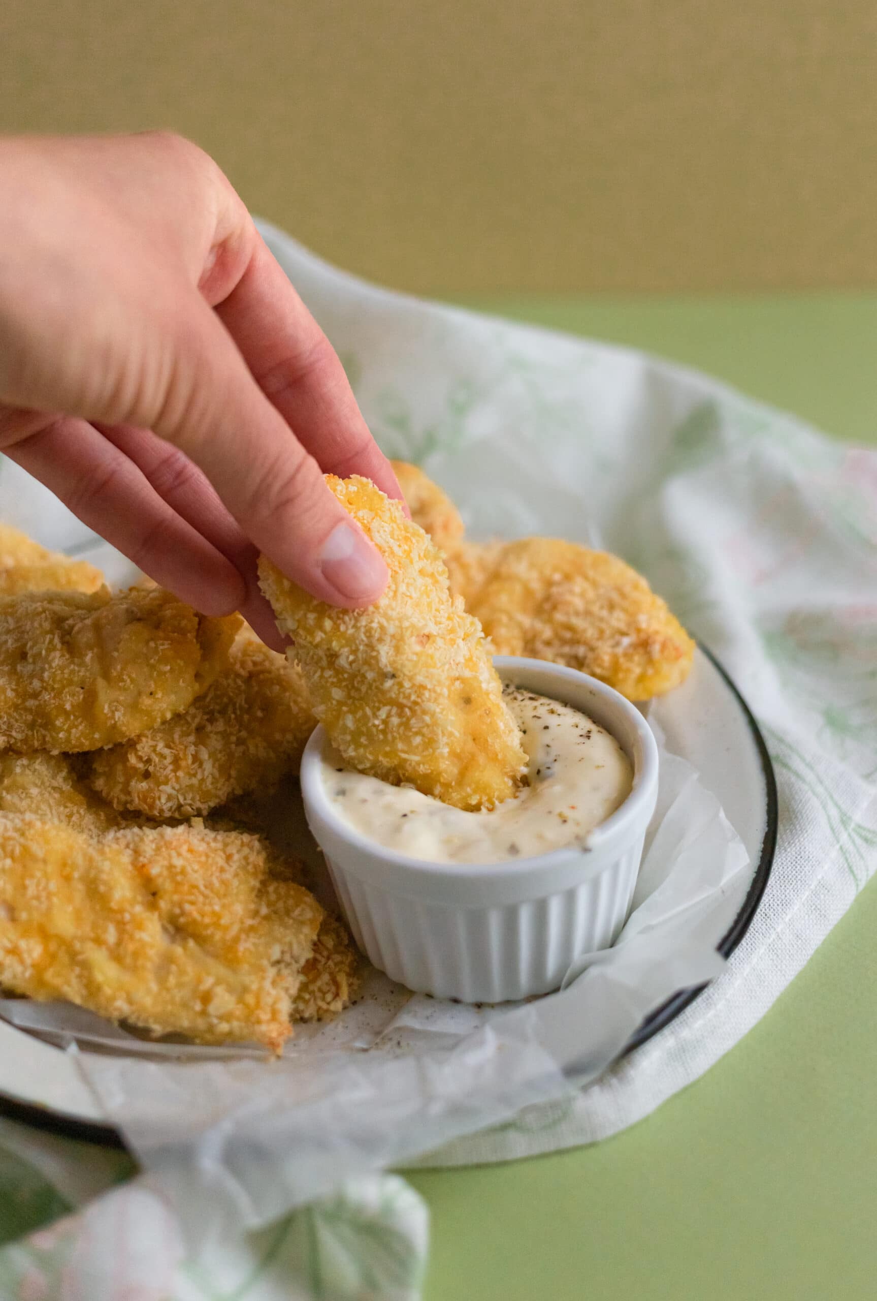 Hand dipping chicken into sauce