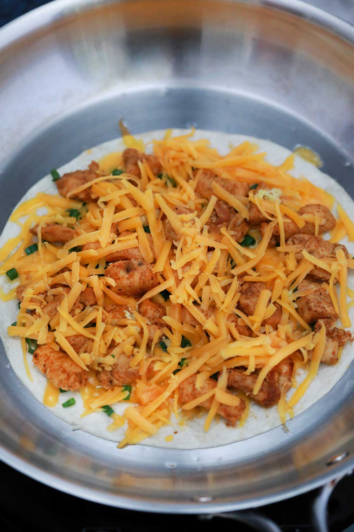 Tortilla topped with chicken in skillet