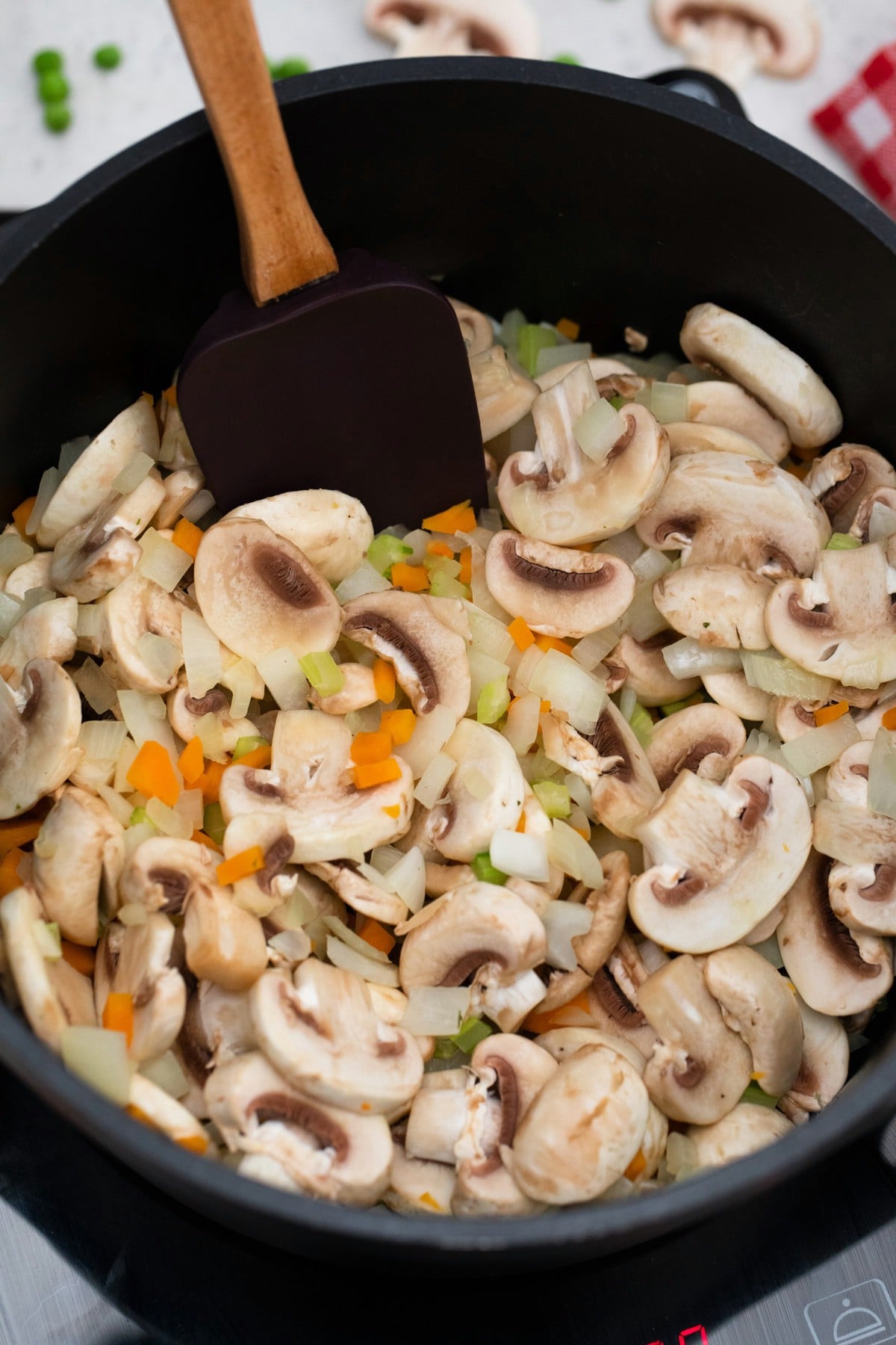 Black spatula stirring mushrooms in stockpot