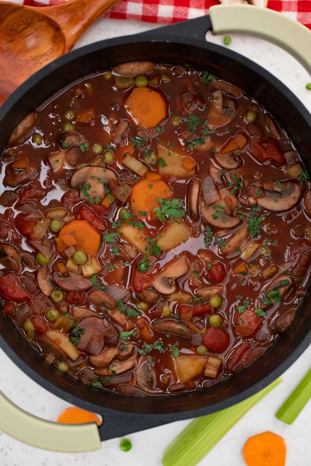 Black Dutch oven of vegetable soup with red broth