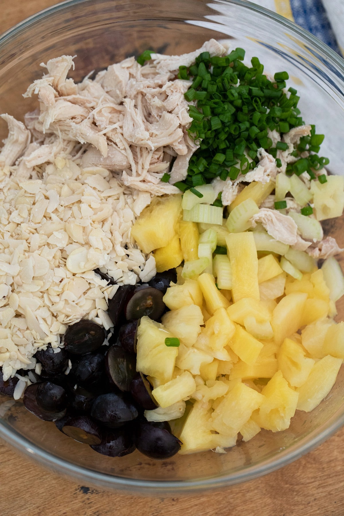 Large glass bowl filled with chicken, grapes, pineapple, and onions