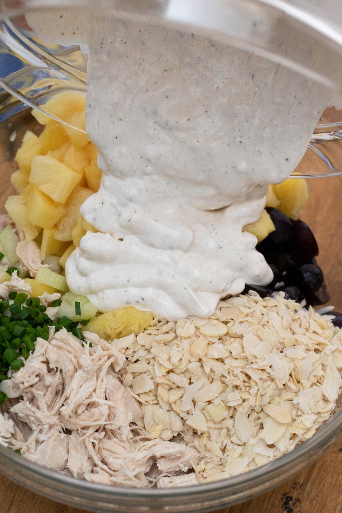 Pouring dressing over bowl of chicken and fruit