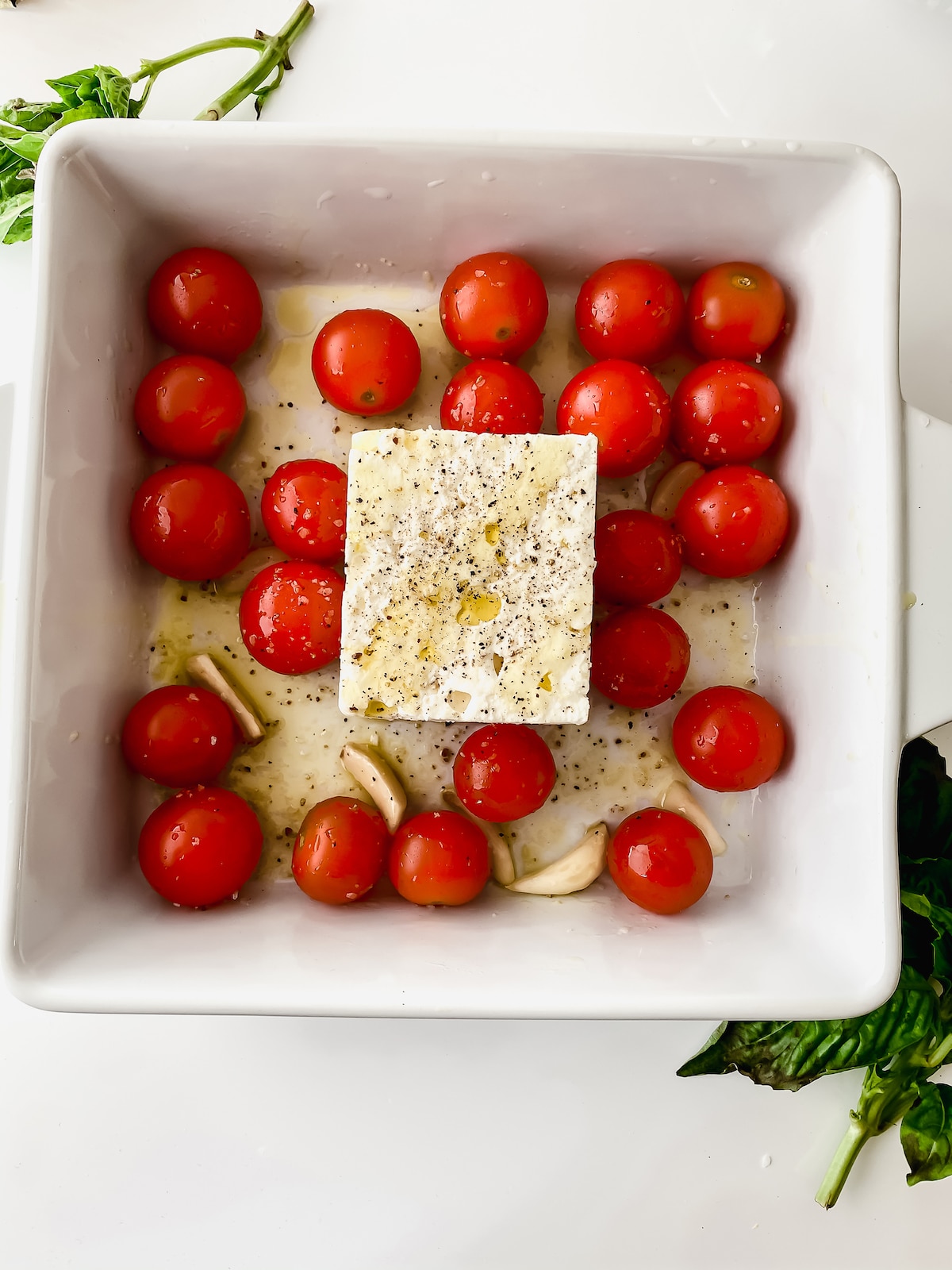 White baking dish with tomatoes and feta