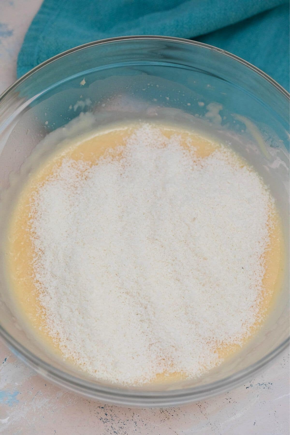Adding coconut to custard in glass bowl