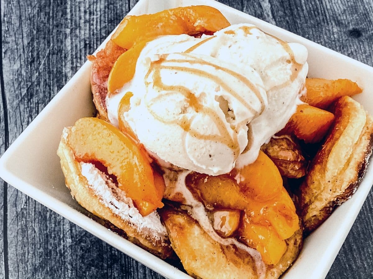 White square bowl with cobbler topped with ice cream on black table