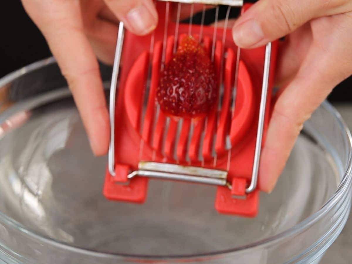 Red berry slicer held over bowl slicing strawberry