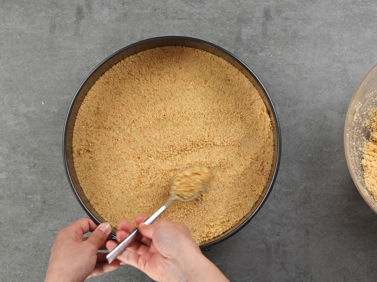 Pressing graham cracker crust down into springform pan