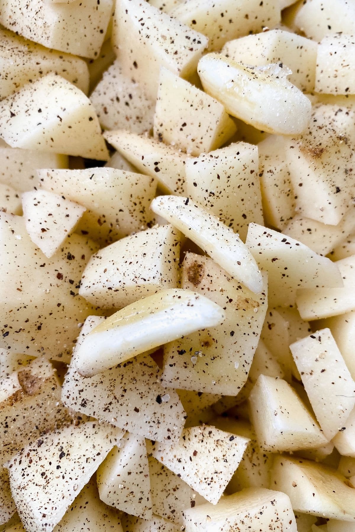 Close up picture of raw potatoes and garlic with black pepper on top