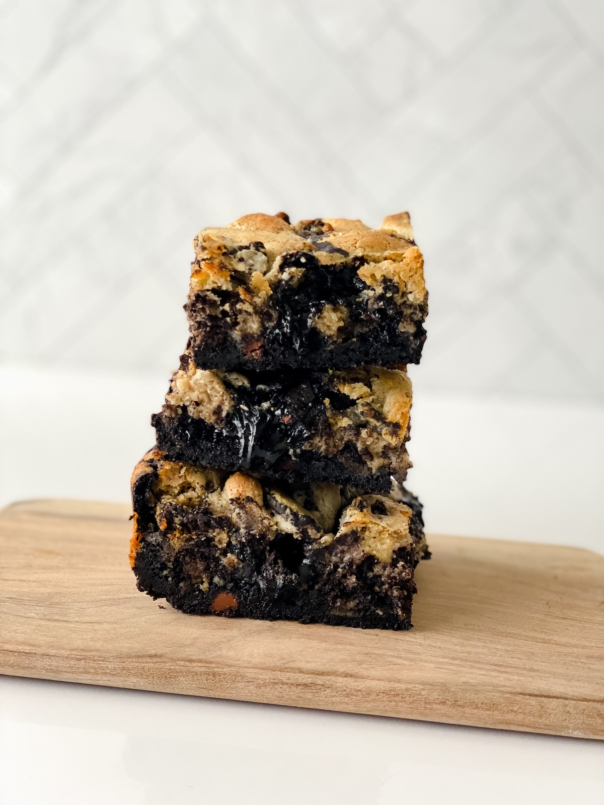 Stack of three brownies on wooden board on white counter