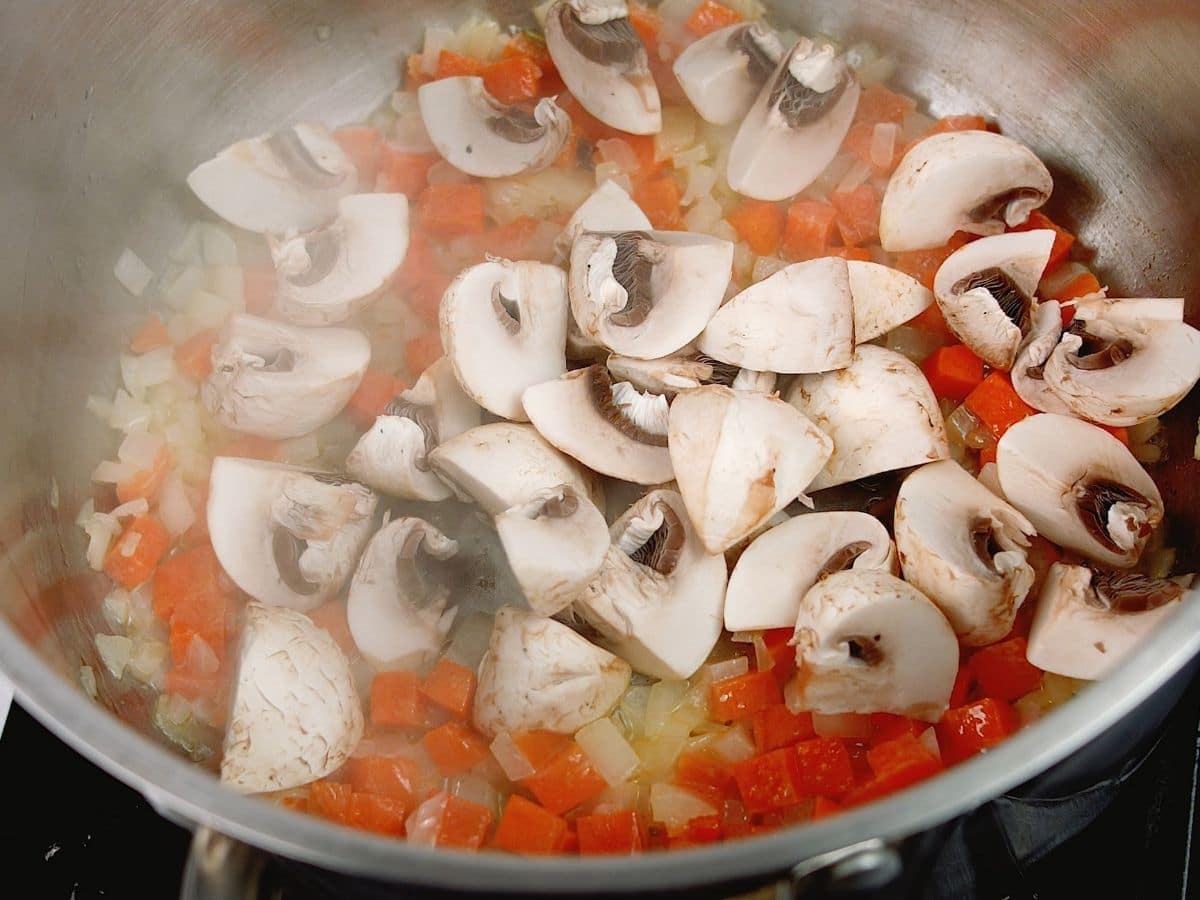 Mushrooms with carrots in pot on hot plate