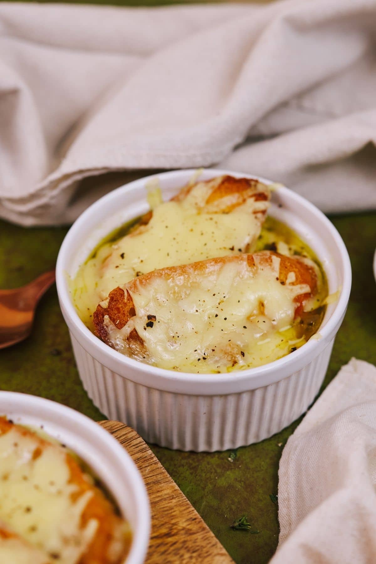 Ramekins on green table filled with french onion soup
