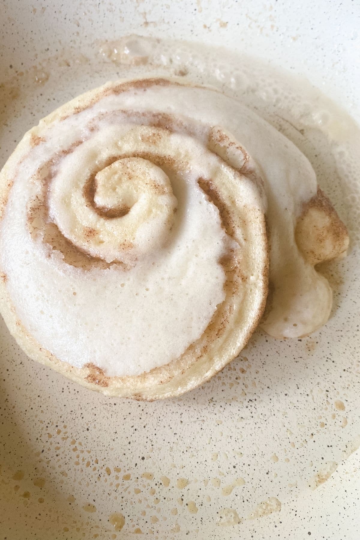 batter over cinnamon roll in skilet