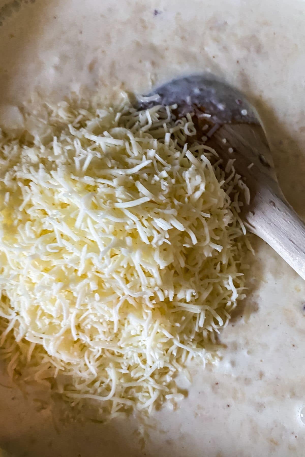 cheese being stirred into sauce in pan