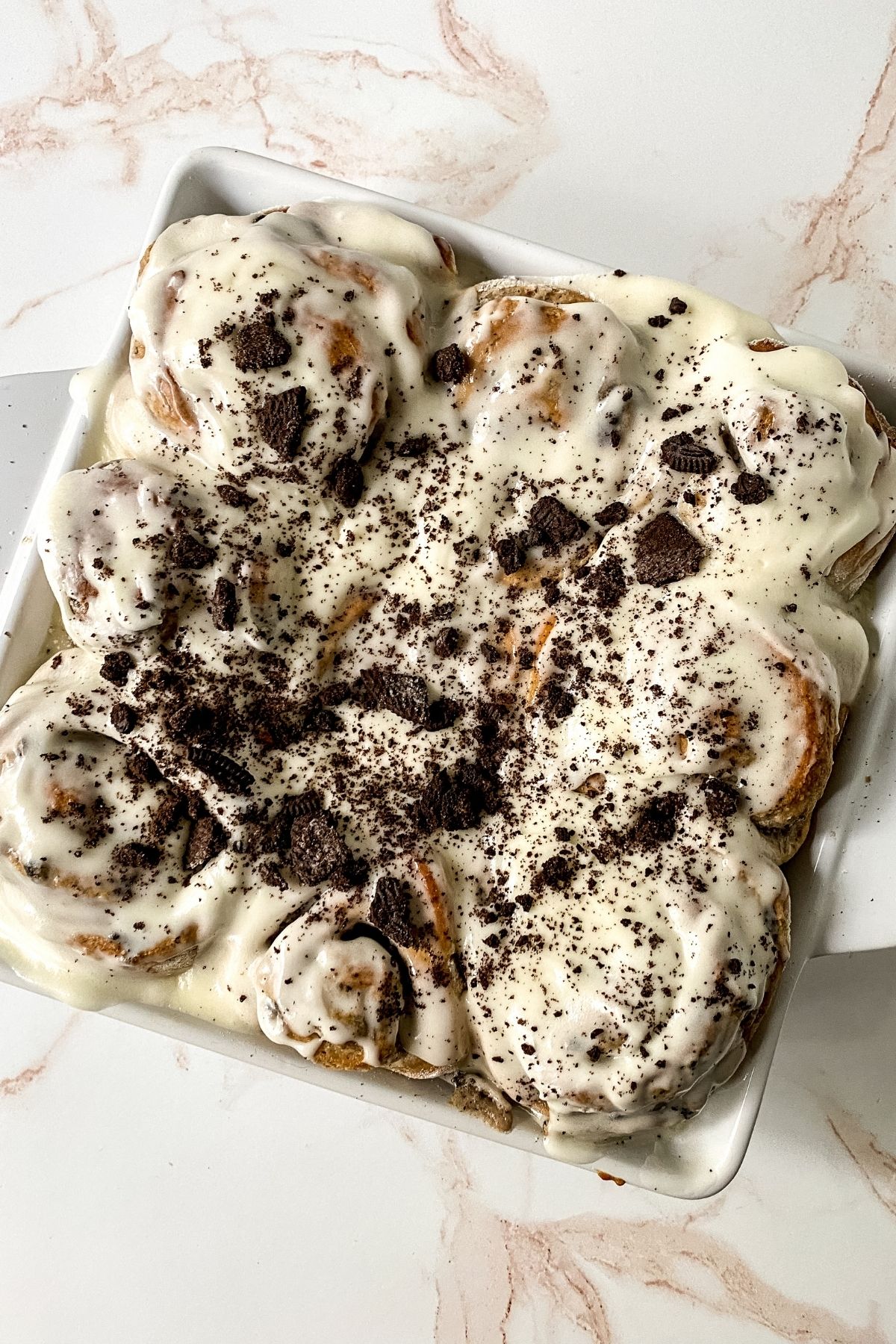 white square pan of sticky buns with oreo cookie crumbs on top