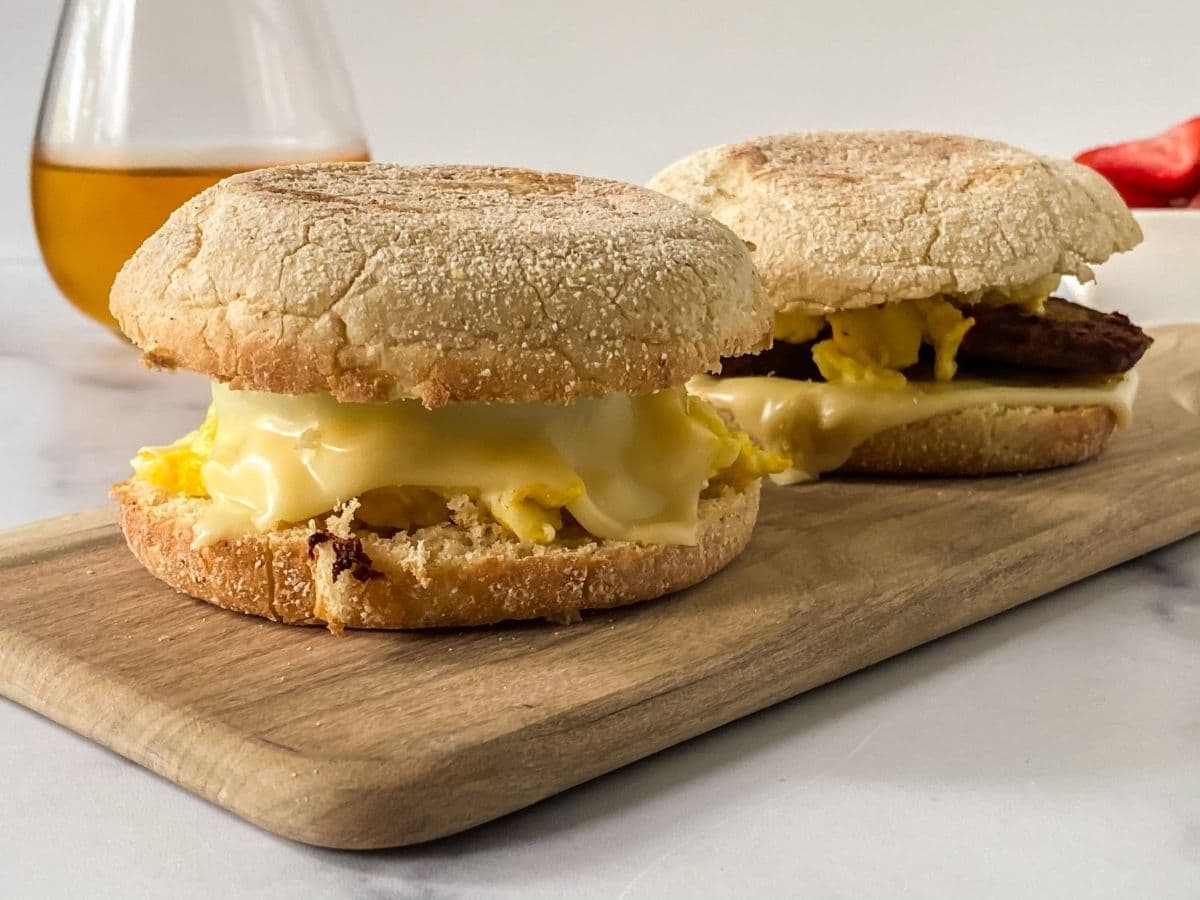 egg and sausage mcmuffin sandwiches on cutting board