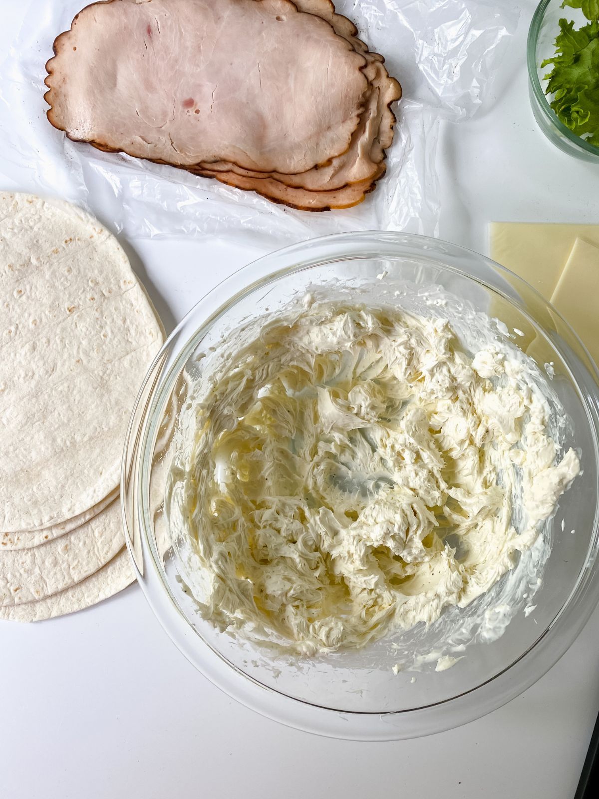 tortillas turkey lunch meat and bow of cheese on table