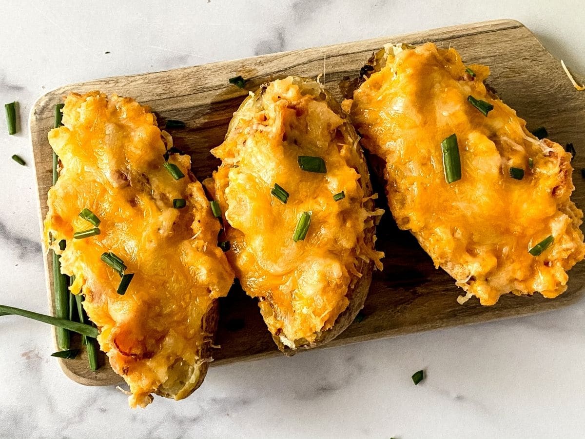 twice baked potatoes on wood cutting board on marble table
