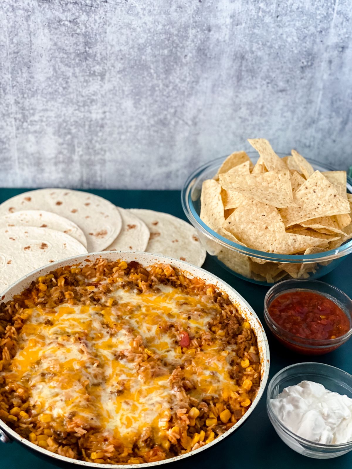 skillet of Mexican rice on table by tortillas with large bowl of tortilla chips