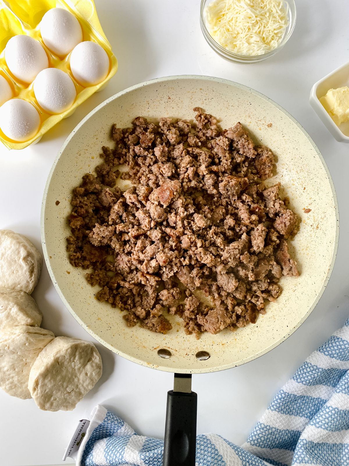 cooked sausage in skillet next to carton of eggs