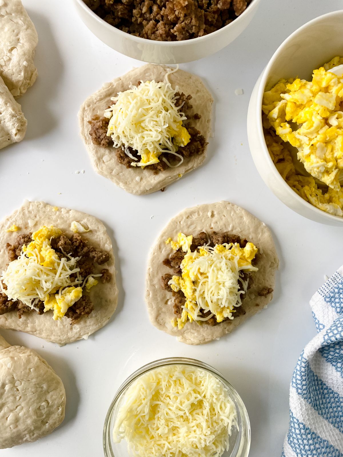 biscuits on white table topped with eggs sausage and cheese