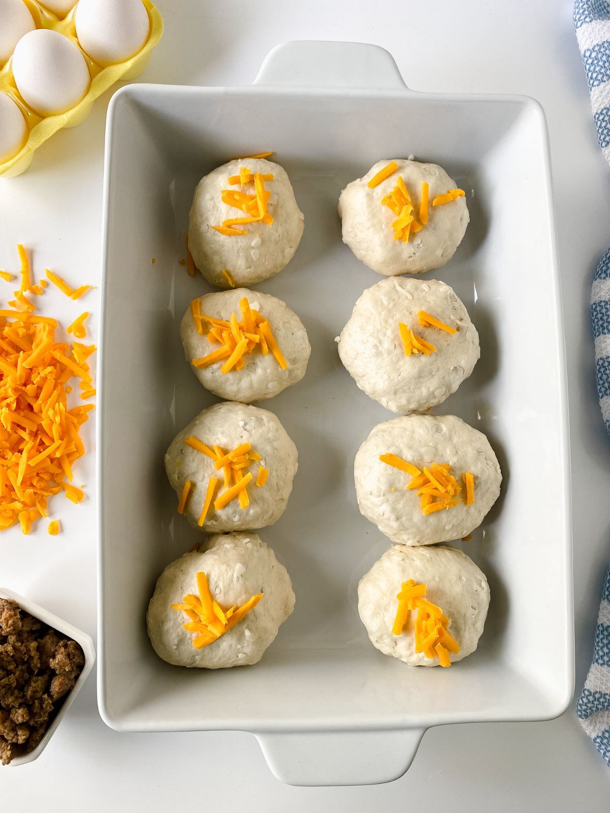 biscuit poppers topped with cheese unbaked in white baking dish