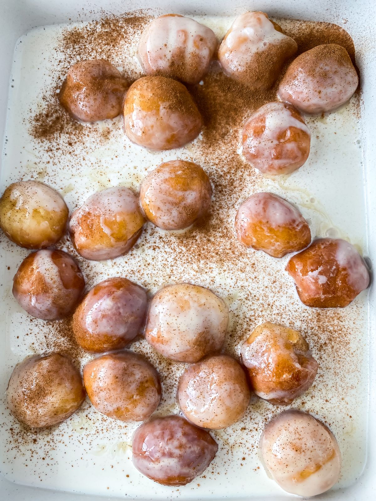 donut holes in pan of cinnamon sugar