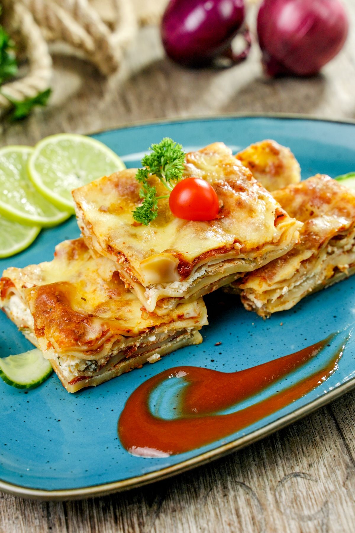 oval teal plate with lasagna and lime slices