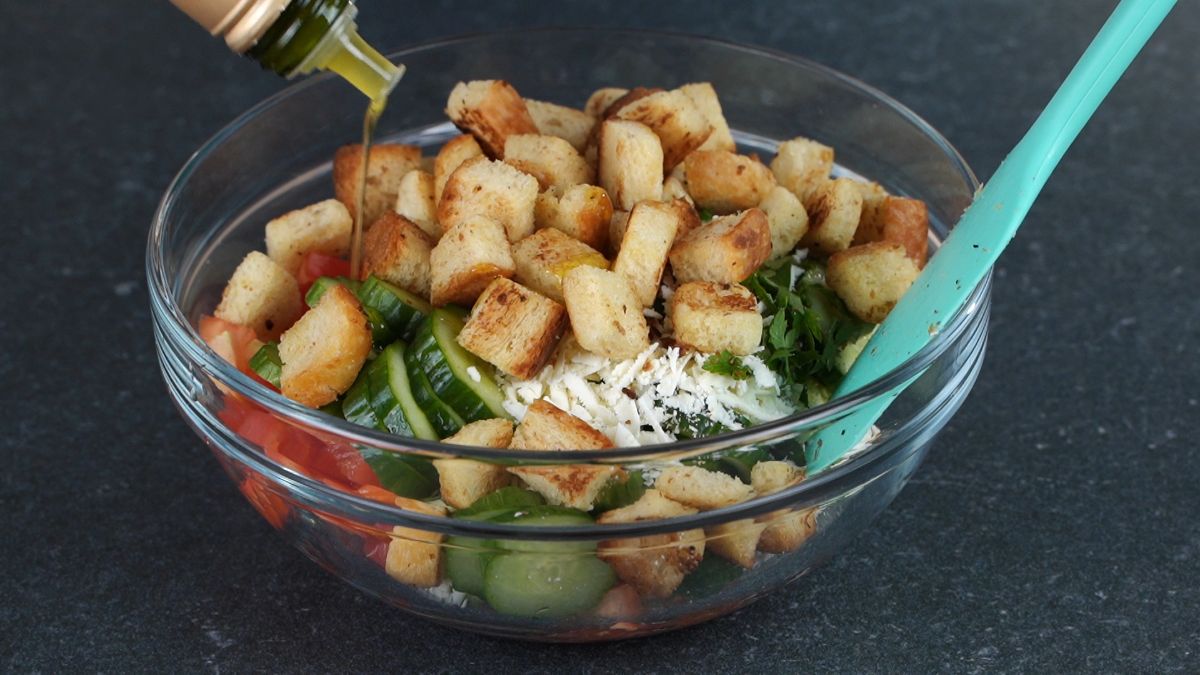olive oil being poured over bread salad