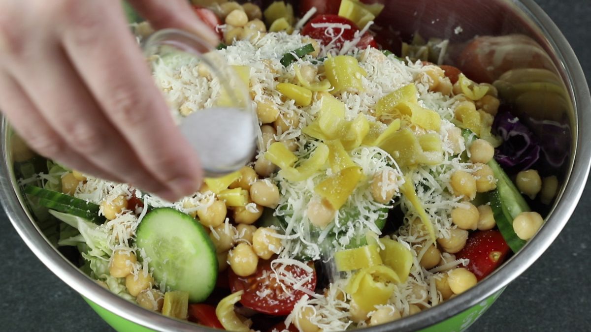 salt in glass bowl being poured over salad