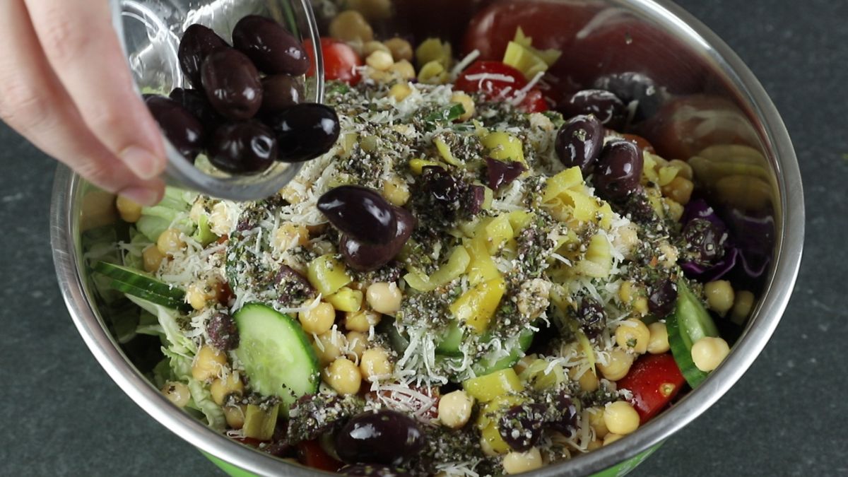 stainless steel bowl of salad being tossed