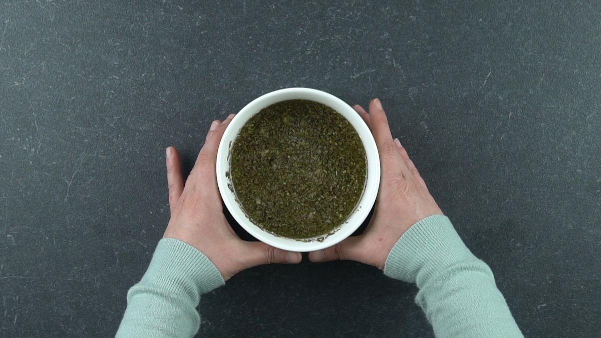 hands holding white bowl of salad dressing