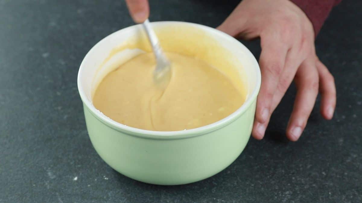 fork whisking tempura batter in light green bowl