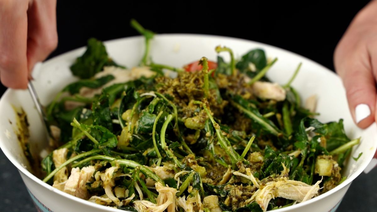 hands holding white bowl of salad