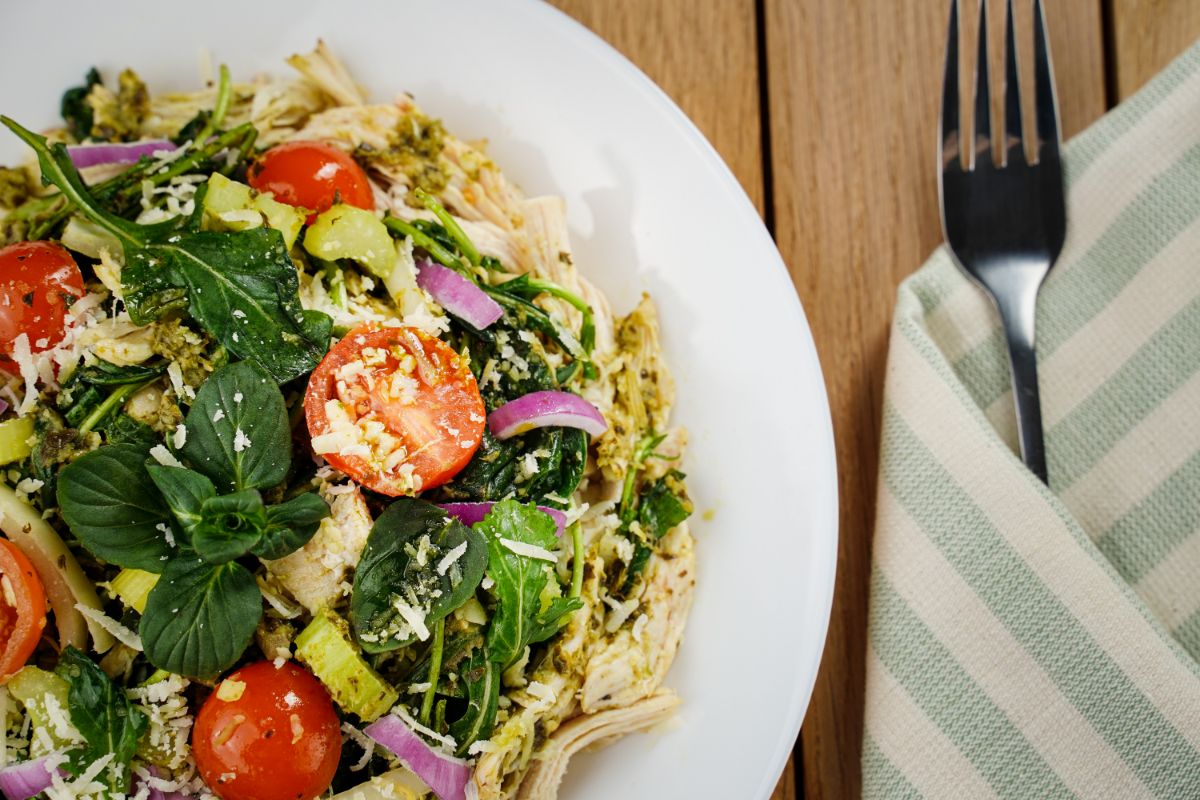 salad on white plate next to striped napkin and fork