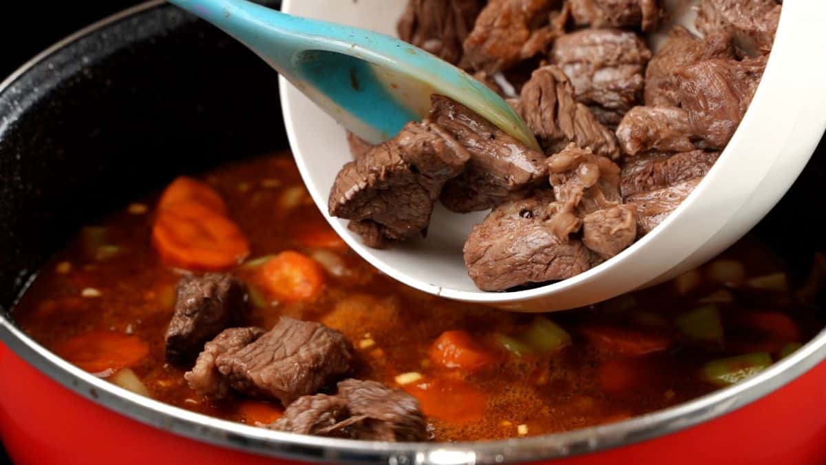 beef being poured back into stockpot with stew