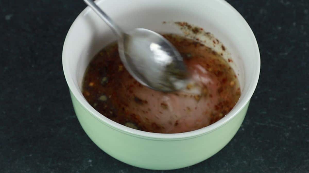 spoon stirring dressing in white bowl
