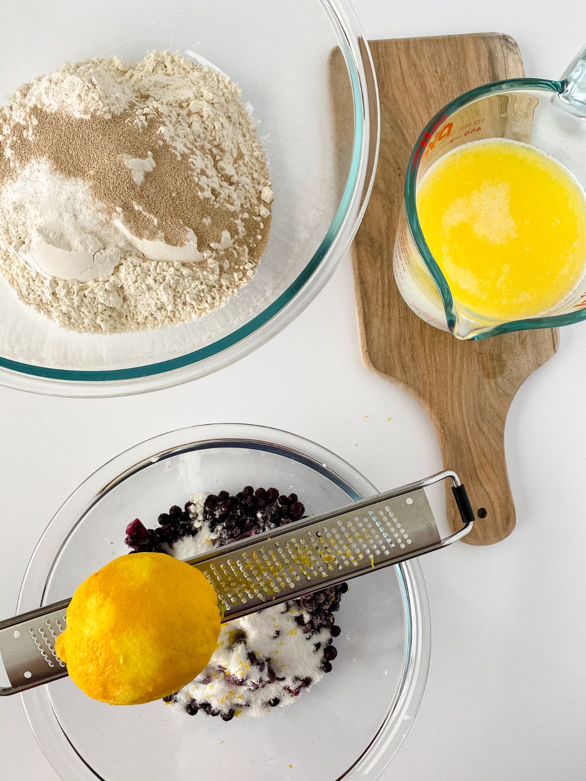 lemon being zested over bowl of blueberries