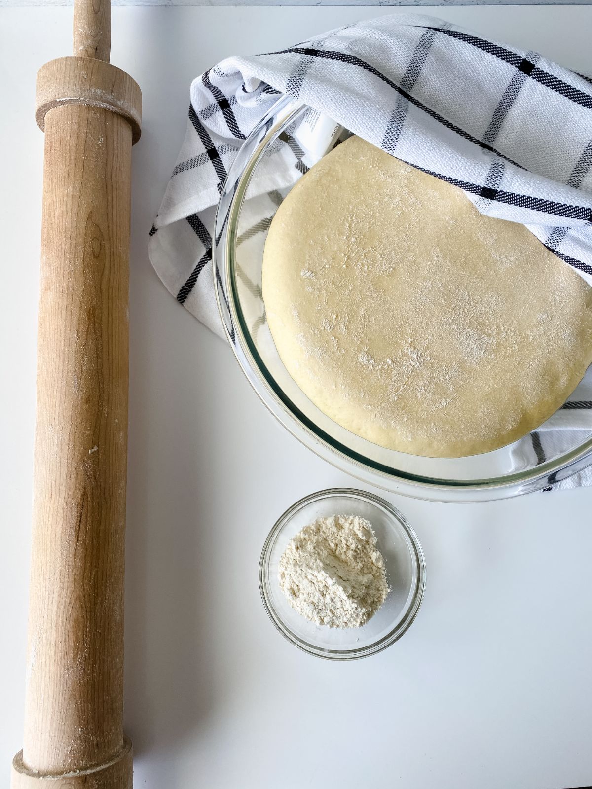 glass bowl of crescent roll dough covered in kitchen towel