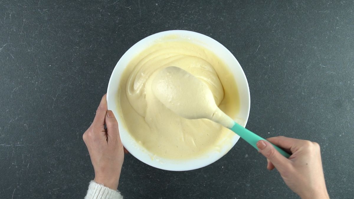 white bowl of cake batter with bleu spoon